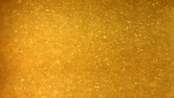 Heldere deeltjes stromen in donker gele vloeistof — Stockvideo