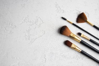 Beton zemindeki fırçaları uydur. Üst manzara. Düz yatıyordu. Güzellik konsepti. Altın ve siyah kozmetik fırçalar.