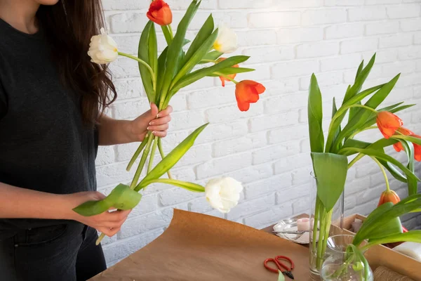 顧客のためのチューリップの創造的な花束の作成に取り組んでいる女性花屋 オンライン注文準備コンセプト 花屋で新鮮な白と赤のチューリップ 花瓶付き花屋の職場 — ストック写真