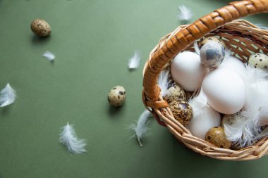 Mutlu Paskalyalar. Geleneksel Paskalya kutlaması kompozisyonu bir sepet yumurta, yeşil arka planda beyaz tüyler. Uzayı kopyala Üst görünüm
