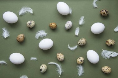 Şık yumurta desenleri. Mutlu Paskalyalar. Yeşil arkaplandaki yumurta ve tüylerin düz görüntüsü. Minimalist stil. 