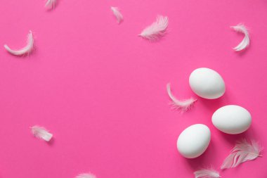 Pembe arka plandaki beyaz yumurta ve tüylerin deseni. Paskalya şablonu. Selamlarınız için yer açın. Moda ve asgari doku. Düz yatıyordu