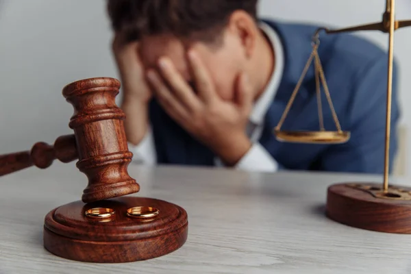 Soltero y triste esposo después del divorcio. Martillo de madera y anillos de primer plano. Concepto de divorcio y separación — Foto de Stock