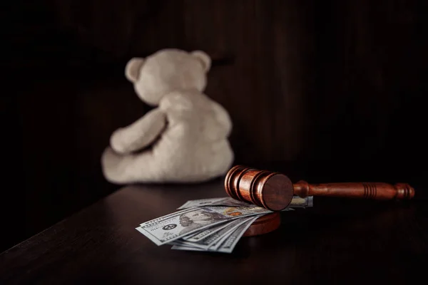 Richtergabel, Dollarnoten und Teddybär als Symbol des Kinderschutzes in einem dunklen Raum. Scheidung, Trennung und Unterhaltsvorschuss — Stockfoto