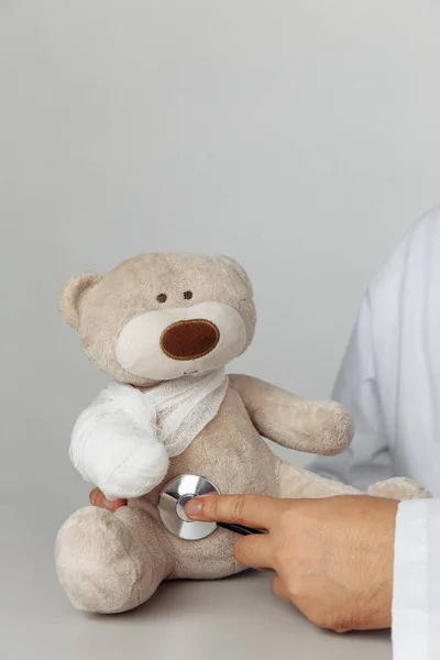 Kinderarts concept. Artsen hand met stethoscoop en teddybeer met verband — Stockfoto