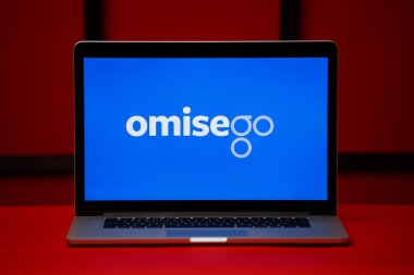 Laptop ekranındaki Tula 06.02.2020 OmiseGo logosu kırmızı arkaplanda izole edildi.