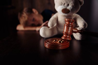 Boşanma ve ayrılma kavramı. Tahta tokmak, yüzükler ve oyuncak ayıyla hayal kırıklığına uğramış çocuk. Aile hukuku