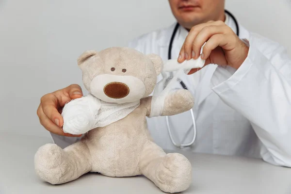 Dokter anak yang serius perban teddy bear di kantor medis. Konsep layanan kesehatan anak Stok Foto