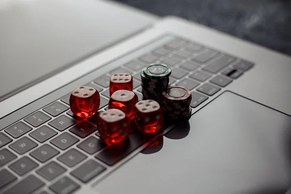 Tema kasino online. Chip judi dan lima dadu merah pada keyboard laptop Stok Gambar