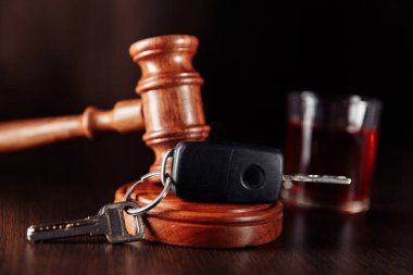 Araba anahtarı, yargıç tokmağı ve yakın plan bardaklı bir şişe alkol. Sarhoş araba kullanma konsepti