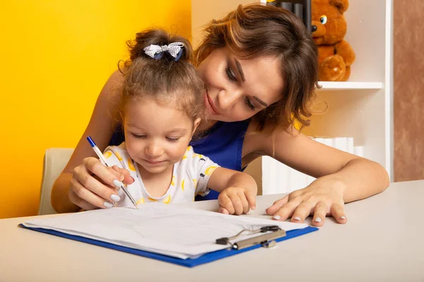 Mère et fille assises au bureau faisant leurs devoirs ensemble. — Photo