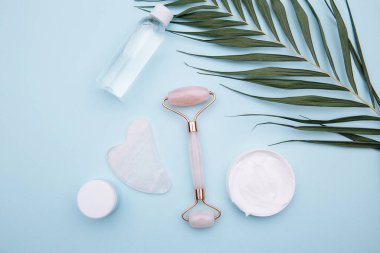 Pembe tekerlekli masaj aleti ve mavi arka planda guaj kazıyıcısı. Güzellik konsepti