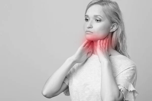 Mujer revisando la glándula tiroides sola. Primer plano de mujer en camiseta blanca tocando cuello con mancha roja. El trastorno tiroideo incluye bocio, hipertiroides, hipotiroides, tumor o cáncer. Asistencia sanitaria. — Foto de Stock