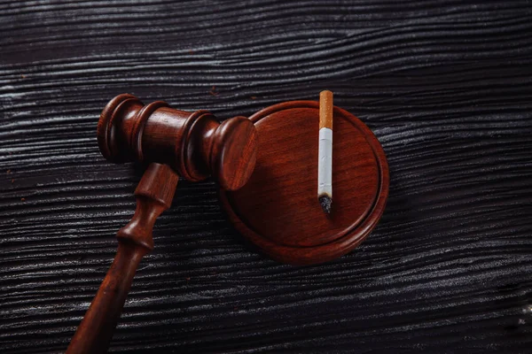 Rokende sigaret en houten rechter hameren op een tafel. Gevaarlijke verslaving en wetgeving — Stockfoto