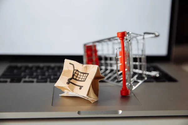 Caja de papel dañada y carrito de compras en un teclado de primer plano portátil. Concepto de entrega. Accidente de envío — Foto de Stock