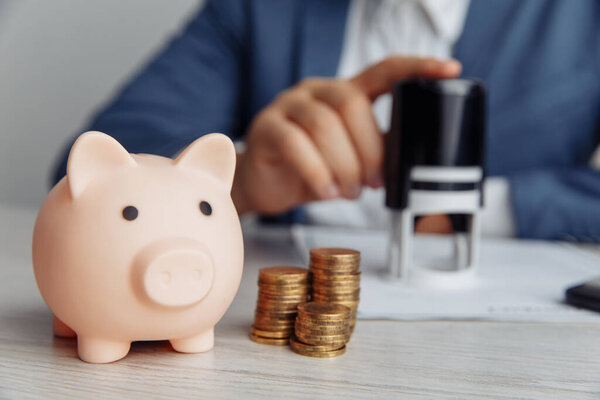Pink piggy bank with stack of coins on wooden desk in office. Save money and management financial concept