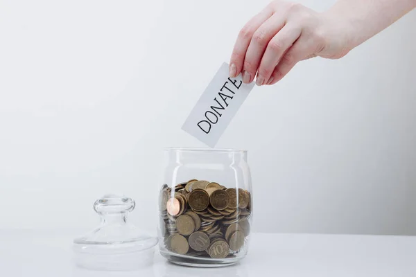 Hand putting paper with DONATE in glass jar. Charity and donation concept — Stock Photo, Image