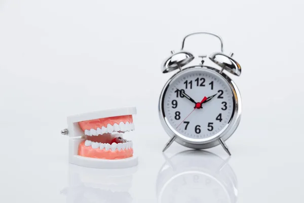 Jaw model and alarm clock on a table. Time to visit a dentist — Stock Photo, Image