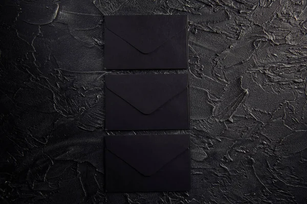 Three black envelopes on a dark background
