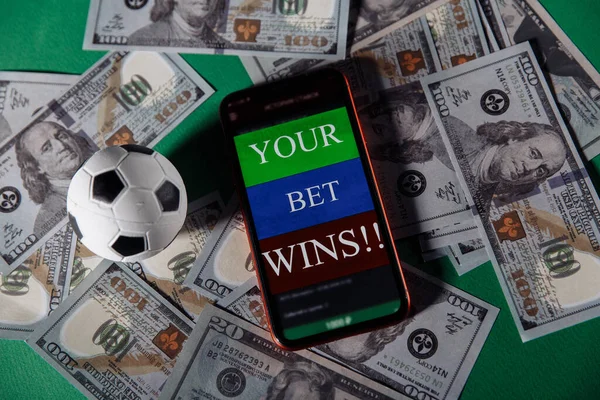 緑の背景にギャンブルモバイルアプリケーションやサッカーボールとスマートフォン。ベットとスポーツ — ストック写真