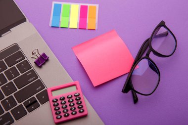 Hesap makinesi, laptop, gözlük ve pembe yapışkan notlu yaratıcı çalışma yeri