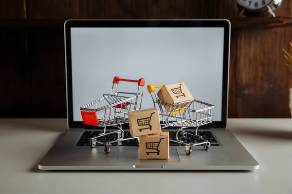 Cajas de papel en carros de supermercado en un teclado portátil. Compras en línea y concepto de entrega — Foto de Stock