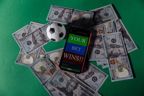 Smartphone met gokken mobiele applicatie en voetbal op groene achtergrond — Stockfoto