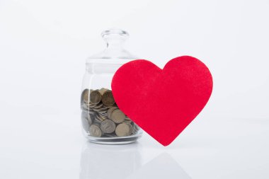 Kırmızı kalp ve cam kavanozdaki bozuk paralar. Sadaka ve bağış konsepti