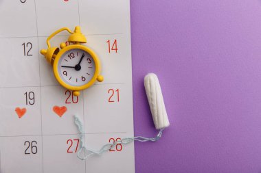 Kadınların adet döngüsü konsepti. Pamuklu ped ve sarı alarmlı takvimde adet dönemi
