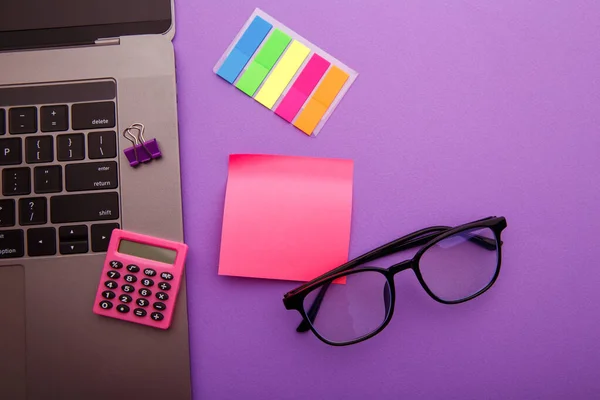 Posto di lavoro creativo con calcolatrice, laptop e nota adesiva rosa — Foto Stock