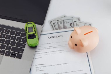 Dizüstü bilgisayarı, kumbarası ve oyuncak arabası olan bir araba al.