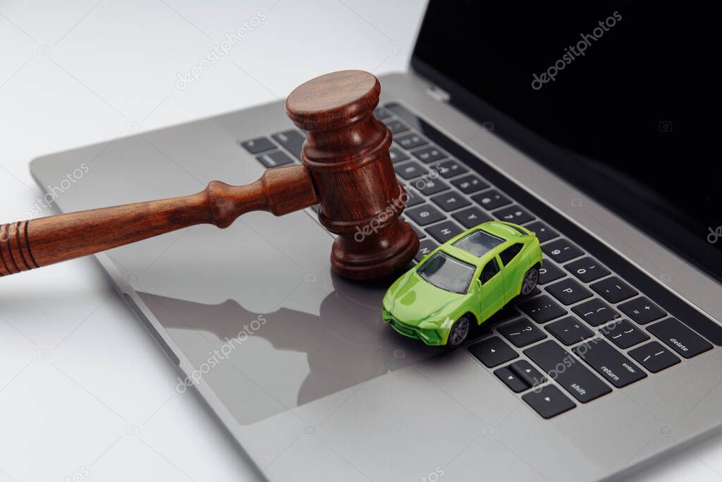 Judge gavel and toy car on laptop computer keyboard. Symbol of law, justice and online car auction.