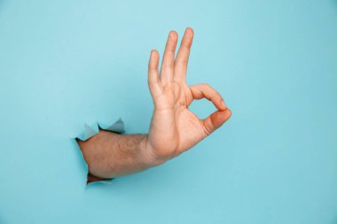 Erkek eli mavi kağıttaki delikten geçer.