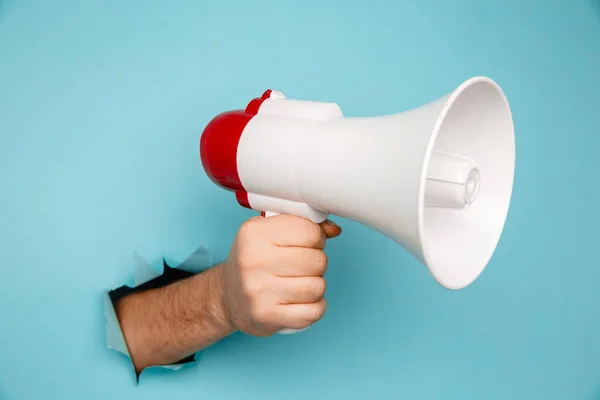 Mans hand arm houden megafoon geïsoleerd door gescheurde blauwe achtergrond — Stockfoto