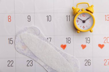 Kadınların adet döngüsü konsepti. Pamuklu ped ve sarı alarm saati olan adet takvimi