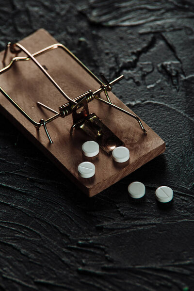 Мышеловка с приманкой в виде таблеток. Наркомания и зависимость от наркотиков. Вертикальное изображение