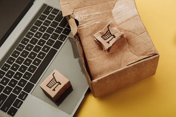Поврежденные бумажные коробки и ноутбук на желтом фоне. Концепция онлайн-покупок и доставки. Несчастный случай с грузом — стоковое фото