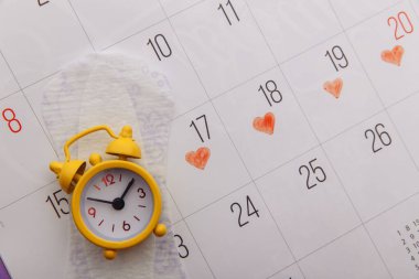 Kadınların adet döngüsü konsepti. Hijyenik ped ve çalar saati olan adet takvimi.