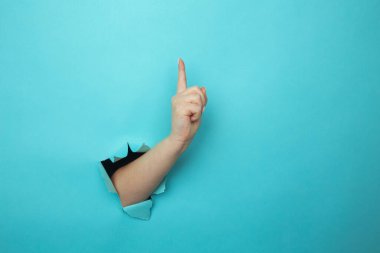 Kadın eli, parmak kaldırarak mavi duvar kırıyor.