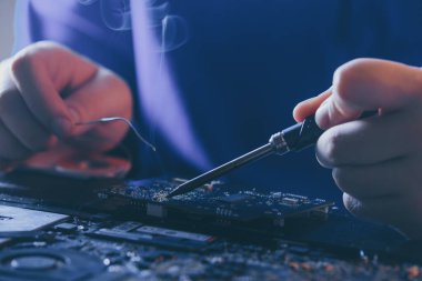 Donanım bakımı ve onarımı. Elektronik ve bilgisayar parçaları yenileme. Mühendis bozuk anakart lehimliyor