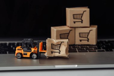 Turuncu forklift modeli ve klavyedeki kırık karton kutu. Kurye servisi ve sevkiyat kazası konsepti