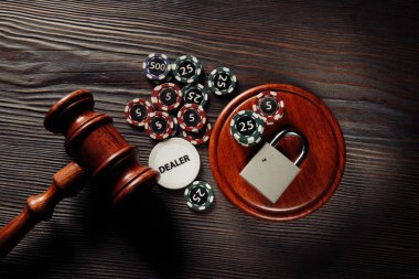 Kumar ve hukuk kavramı. Tahta arka planda asma kilitle çip ve yargıç tokmağı oynuyorum.