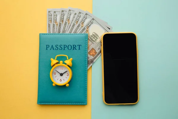 Planejamento de viagens com smartphone e passaporte com dinheiro em fundo azul amarelo — Fotografia de Stock