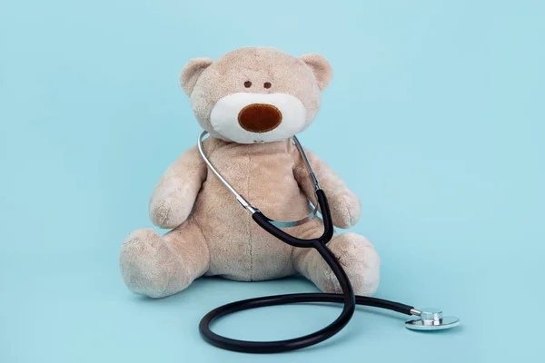 Pediatrician concept. Stuffed Bear animal presented as a pediatrician holding a stethoscope isolated on blue background