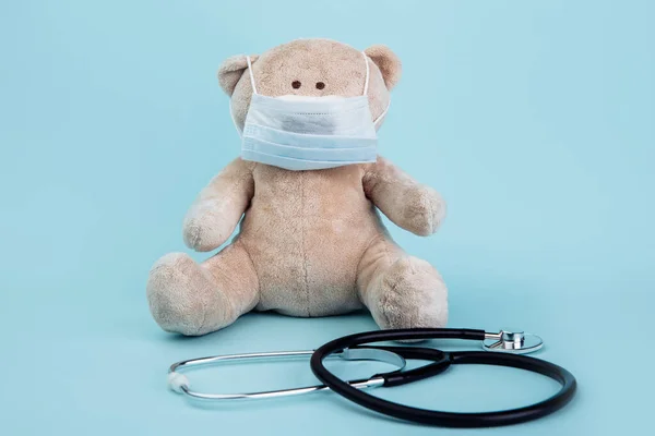 Gevulde Beer dier in masker met stethoscoop geïsoleerd op blauwe achtergrond. Thema kindergezondheidszorg — Stockfoto