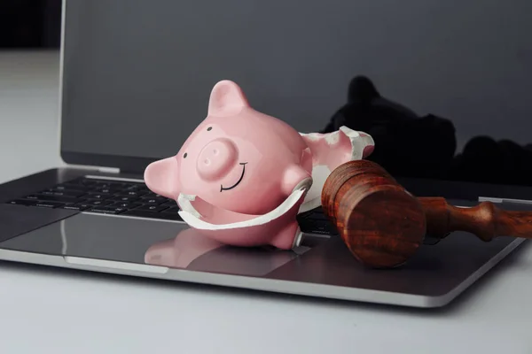 Broken piggy bank and wooden gavel on keyboard. Business, finance and bankruptcy concept