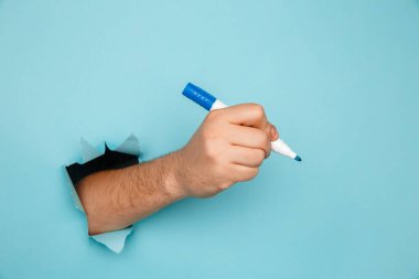 Bir adam kırık bir duvara kalem yazar.