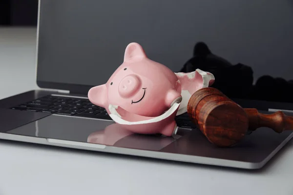 Broken piggy bank and wooden judge gavel on laptop. Business, finance and bankruptcy concept