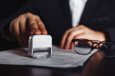 İş adamı önemli bir sözleşmeyi onaylar. Belgeler ve pullar masanın üstünde. İş konsepti