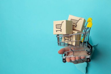 Kadınların el ele tutuşması bir alışveriş vagonunda kağıt arka planda teslimat kutularıyla olur. Satış konsepti